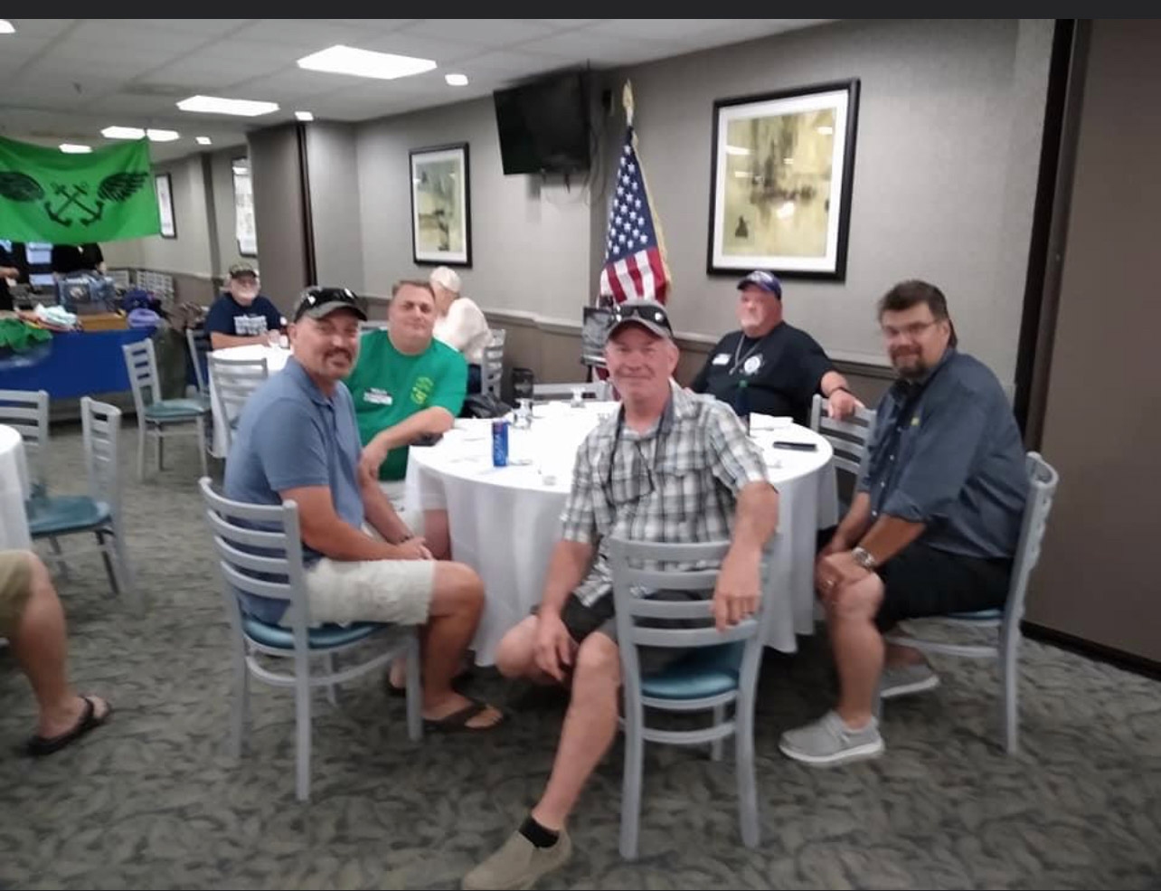 A group of men sitting at a table with a flag on it.