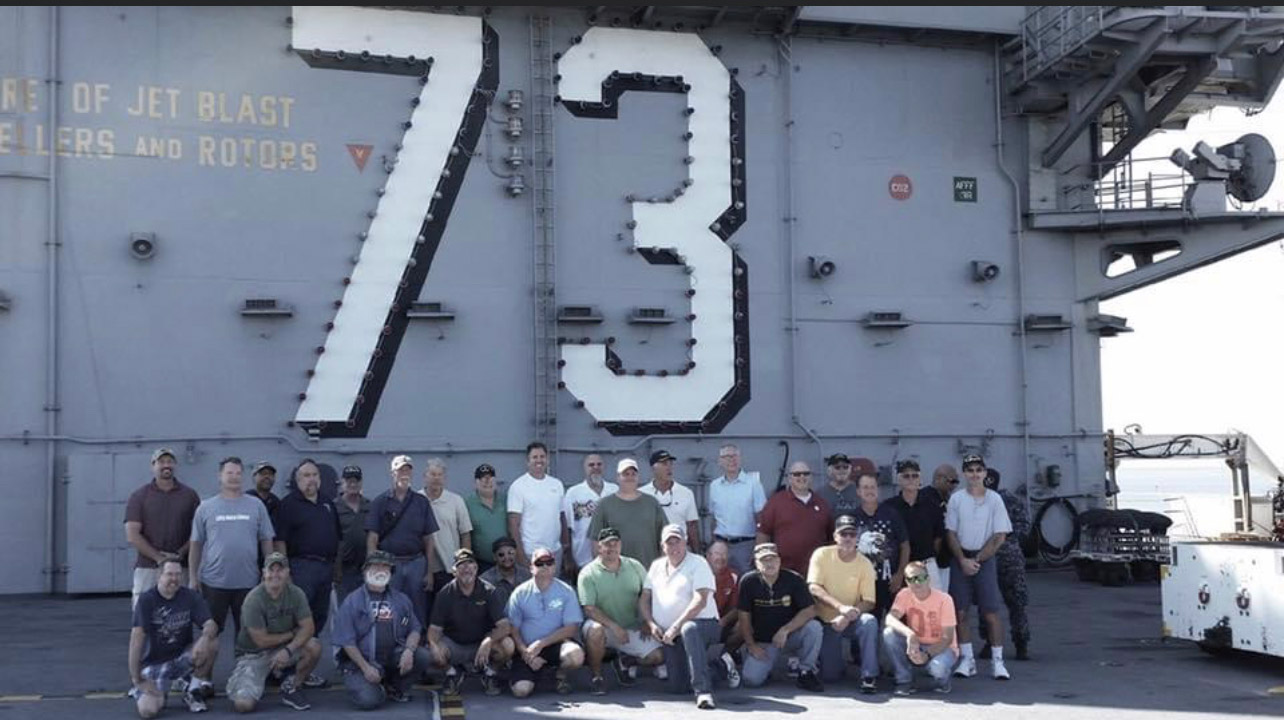 A group of people standing in front of a large number sign.