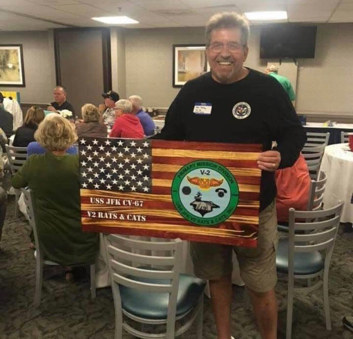 A man holding up an american flag and a sign.