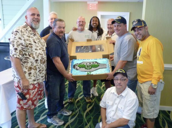 A group of men holding up a box with a fish inside.